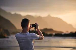Man during photographing landscape with cliff at sunset