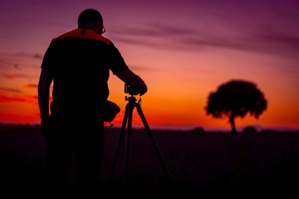 Fotográfo en un campo abierto tomando fotografía al atardecer