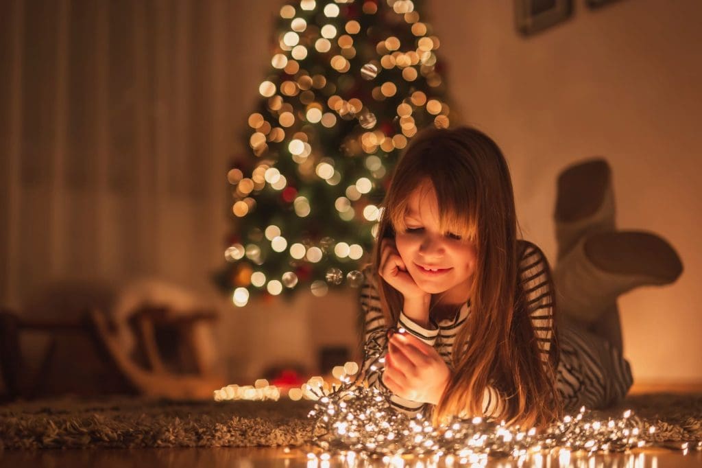 Pequeña niña con iluminación en la cara por luces navideñas 