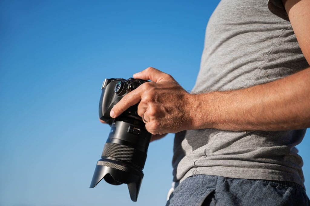 Fotografo hombre revisando parámetros en panatalla de cámara, ajustes de exposición, profundidad, velocidad, etc.