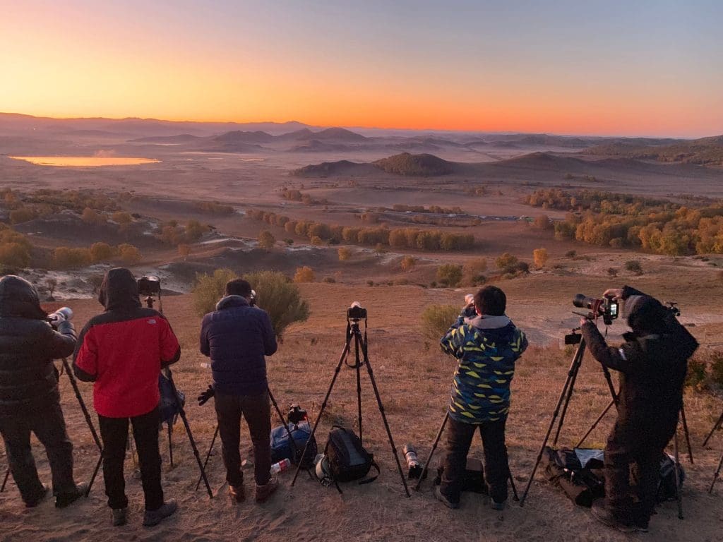 Grupo de personas tomando fotografías al amanecer