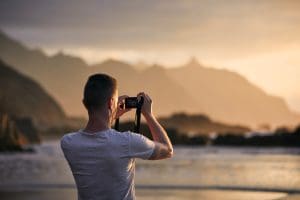 Man during photographing landscape with cliff at sunset